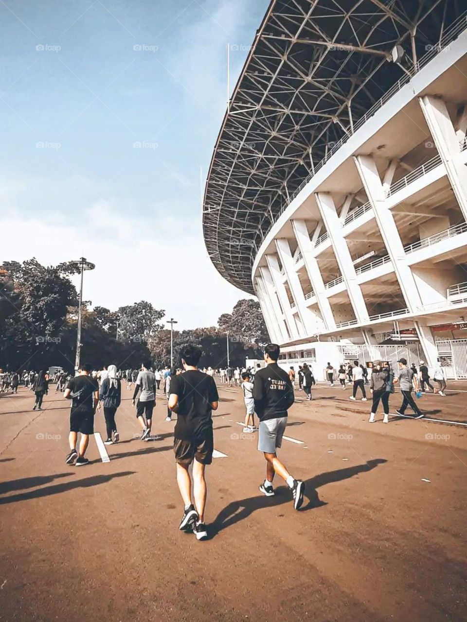 Close-up view of a group of people walking near a large stadium during the day