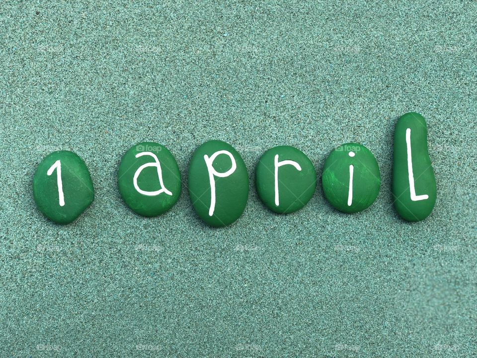 1 April, calendar date with green colored stones over green sand 