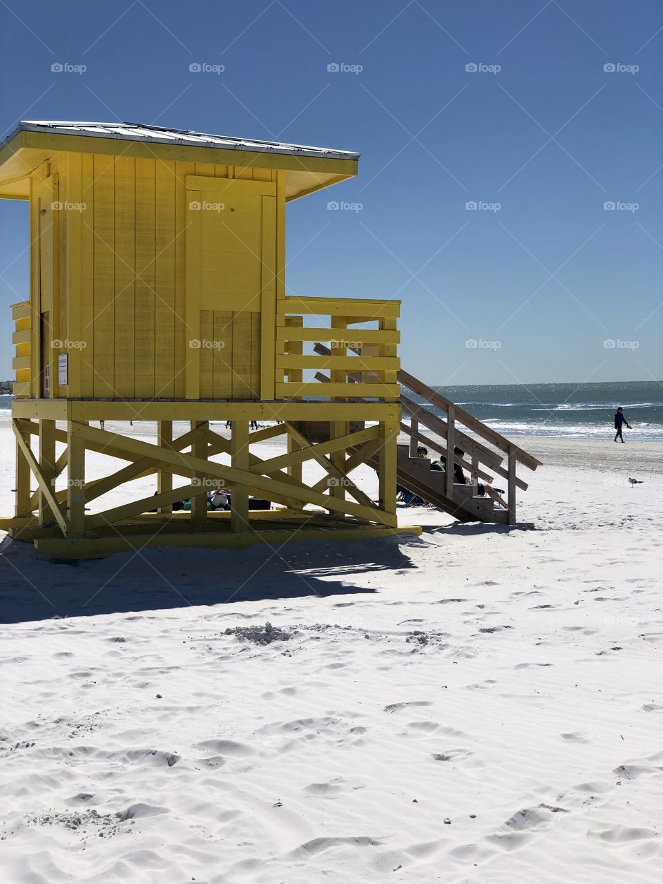 Yellow lifeguard stand on white beach 
