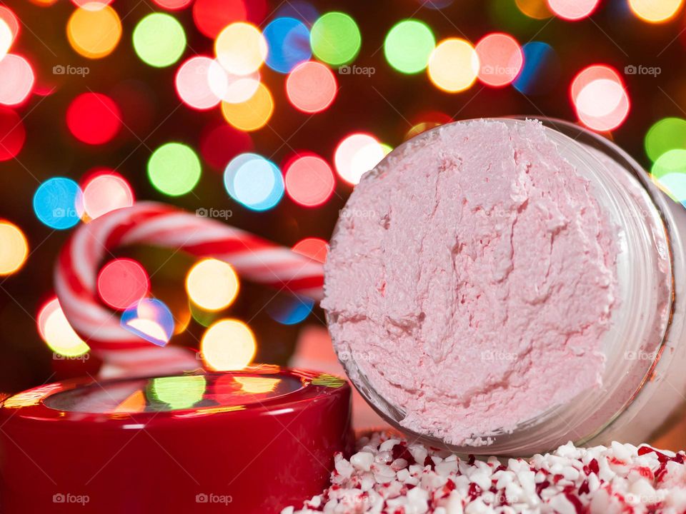 Peppermint Sugar Scrub in front of Christmas lights with bits of candy cane.