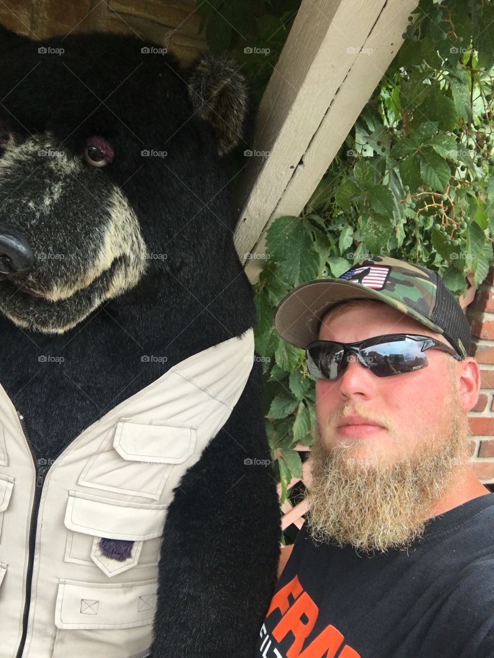 Just a bearded man and a black bear, in a vest.