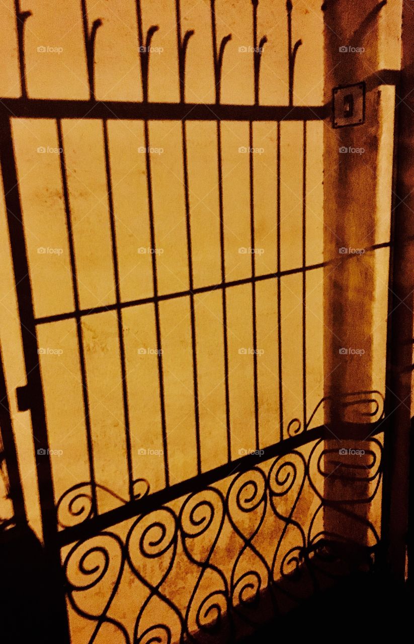 Shadow of iron gate on yellow wall