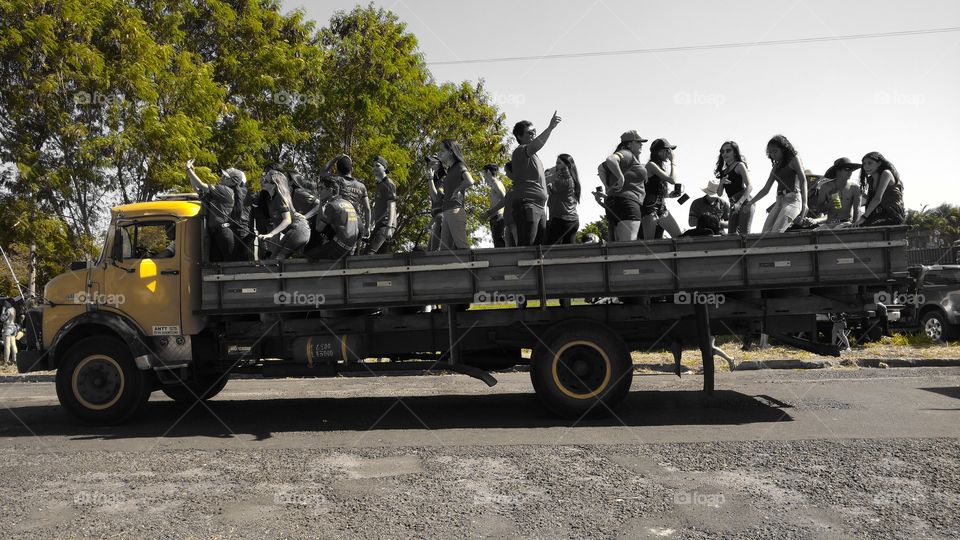 Caminhão amarelo com pessoas em confraternização.