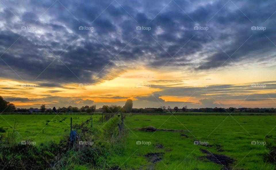 Stormy clouds rolling into a sunset or sunrise Countryside farmfield landscape 