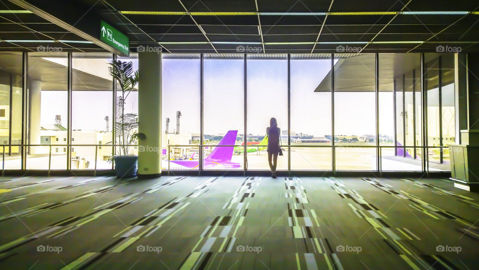 Girl at the airport window looking to the plane