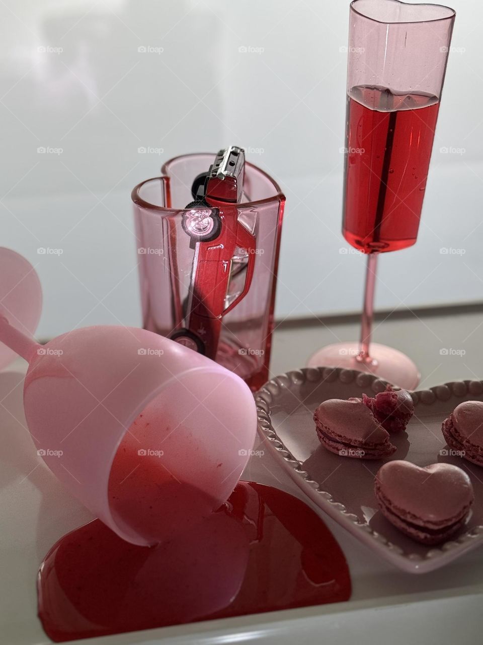1967 maroon Ford Mustang in a heart shaped pink glass with a pink plastic goblet of red red wine a. spilled glass of red goo and heart shaped macarons on a pink ceramic trinket dish