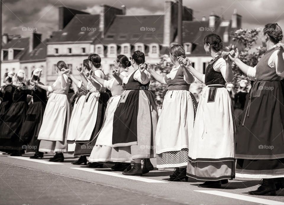 Sepia shot of women dancer's parade dressed in Breton traditional costumes at the Cornouaille festival in Quimper