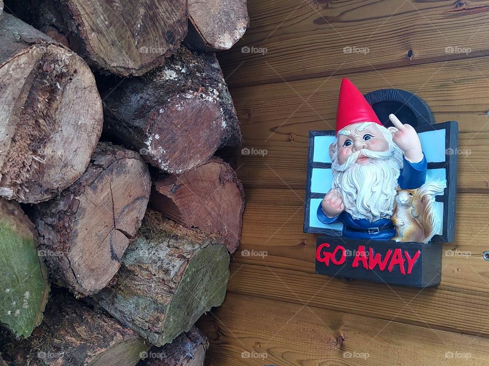 Next to a pile of wood, a coarse garden dwarf invites us to go elsewhere