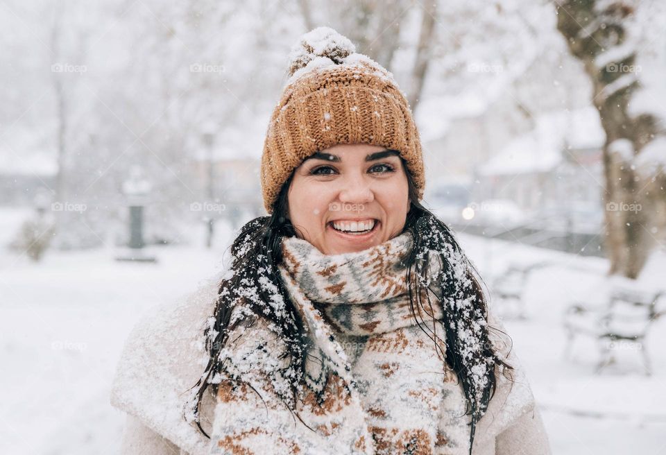 Portrait of happy young woman wearing winter clothes on a snowy day in winter