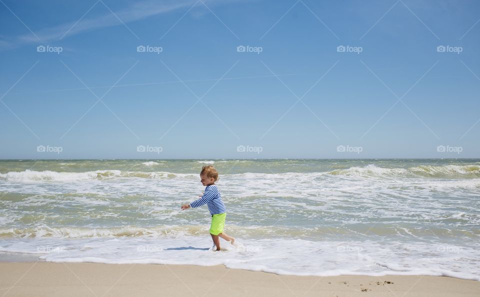 Little boy run and play at sea beach 
