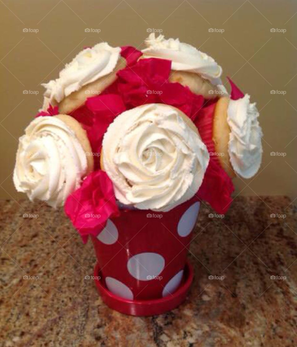 A cupcake bouquet in a vase with icing piped on like roses. 