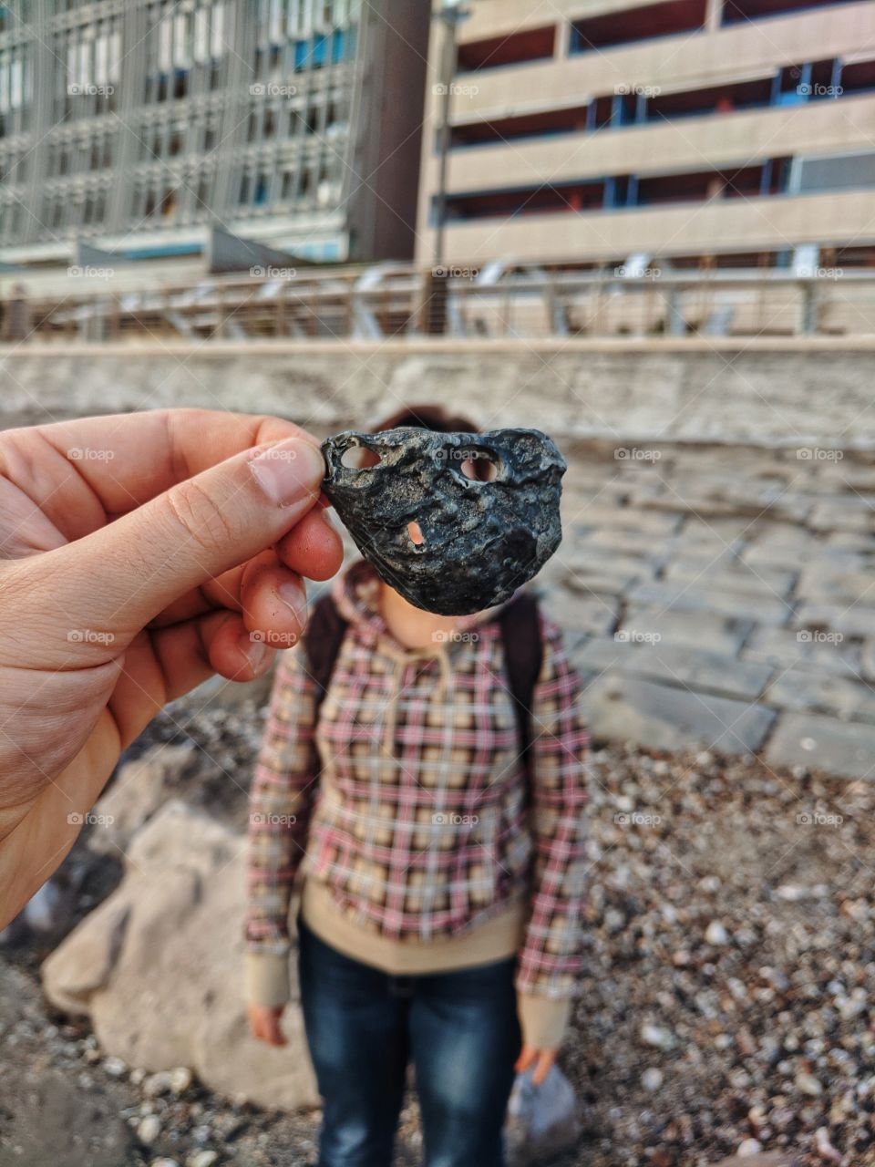 Funny photo session, where the guy's hand covers the girl's face with a shell at the Adriatic seaside on vacation.