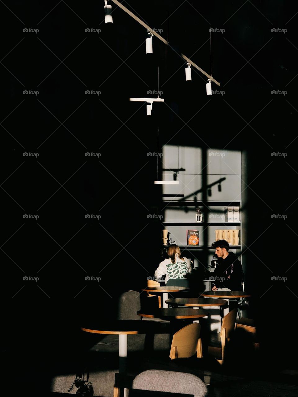 Two people sitting in modern cafe in sunny day