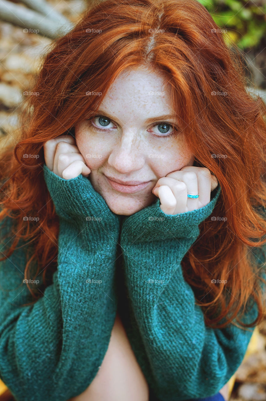 Redhead funny woman with freckles and blue eyes looks at the camera.