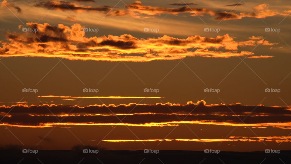 Bands of tangerine clouds adorn the sky during sunset.