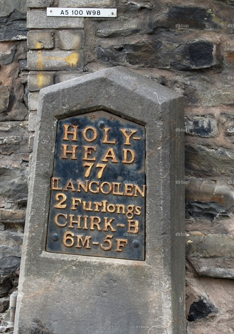 Old milestone indicating distance to Holyhead, Llangollen and Chirk in miles and furlongs. 