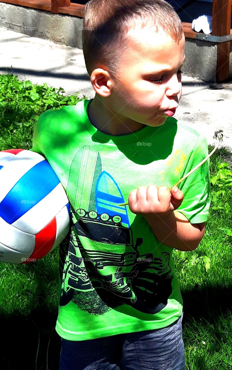 The one thing that all kids to do is blow the dandelions. innocence not a care in the world carrying his ball enjoying the sun. my son is autistic and adopted and he has my whole world with his sister