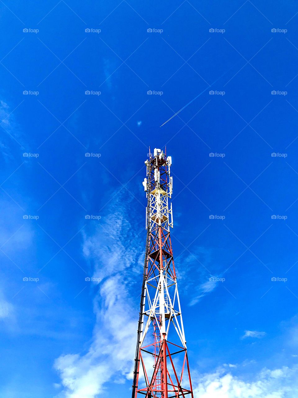 Tower with communication antennas against the blue sky with clouds