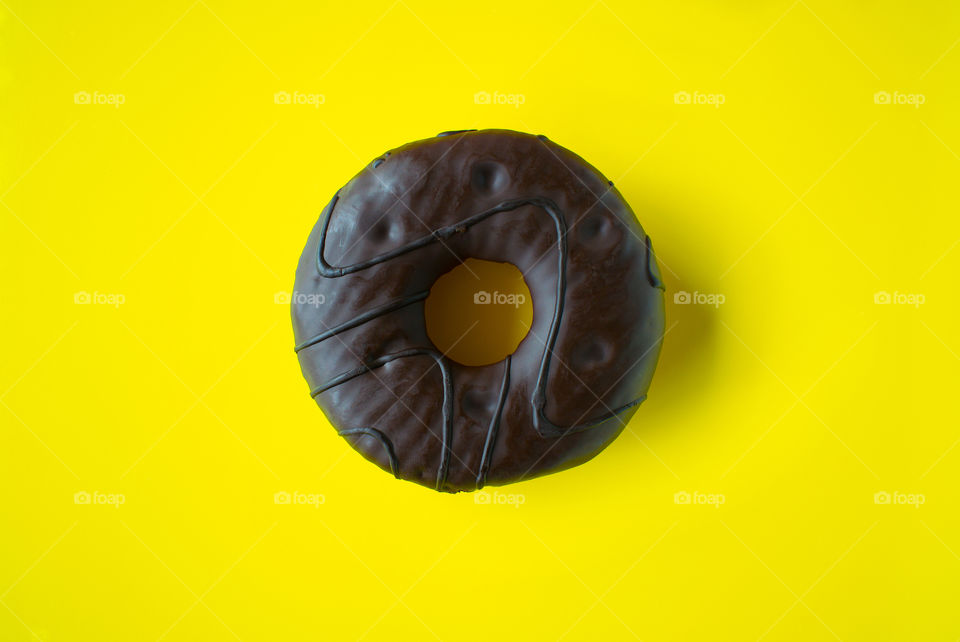 Tasty chocolate donut on the colorful yellow background