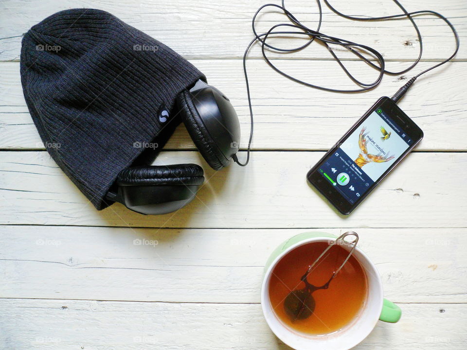 cup of tea, headphones, hat and smart phone on the table