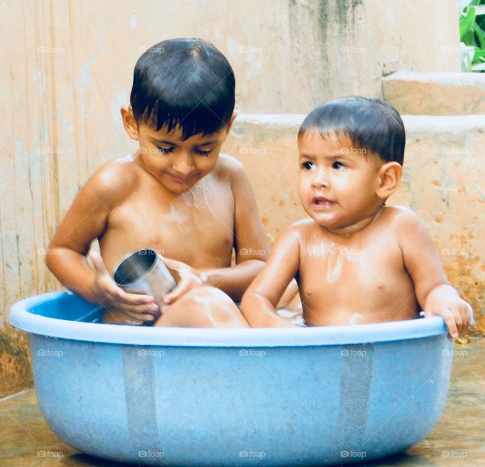 Two sisters having fun while taking bath together in scorching summer 