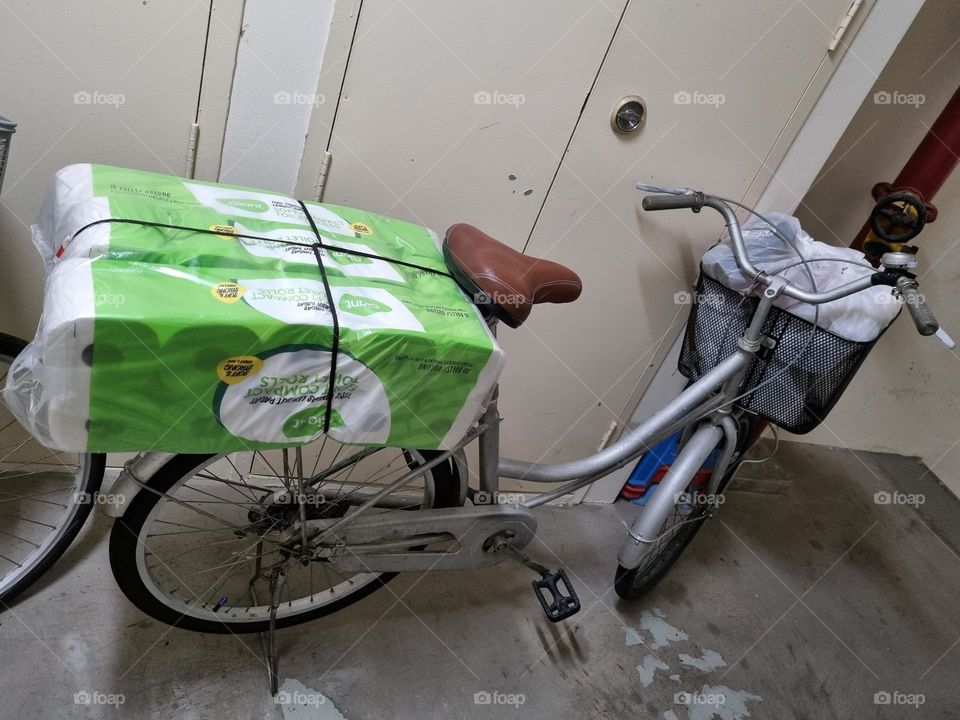 Bicycle with a bag of toilet rolls secured with black shoelaces