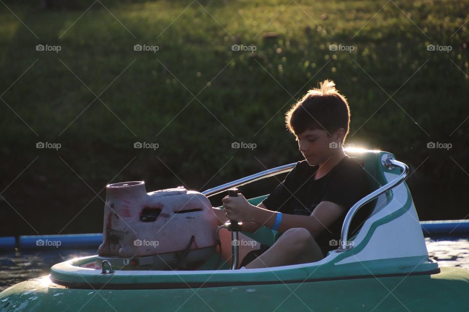 Boy riding in bumper boat at golden hour