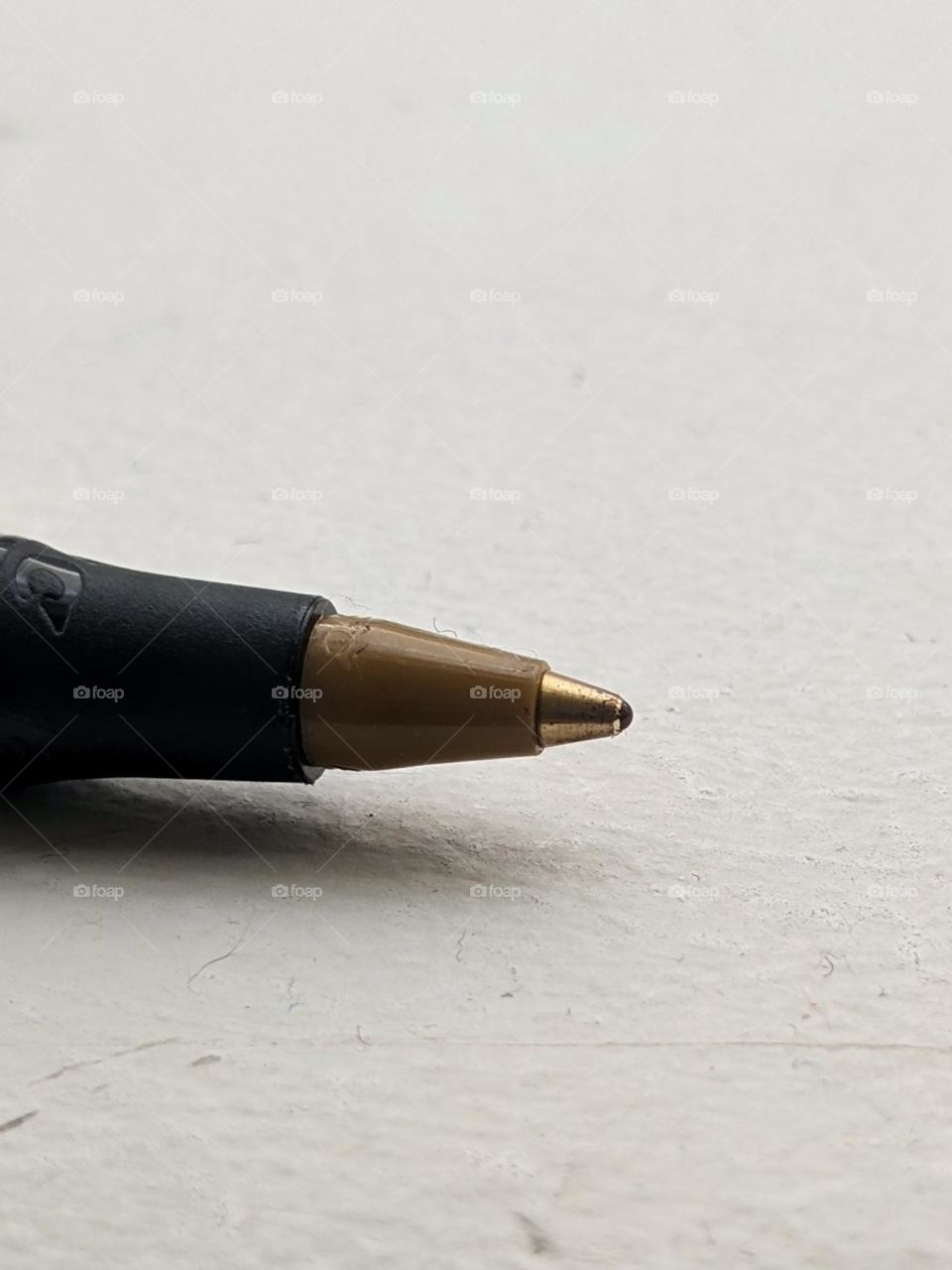 macro shot of a pen tip sitting on a white surface. a small hair can be seen stuck to the side of the pen tip.