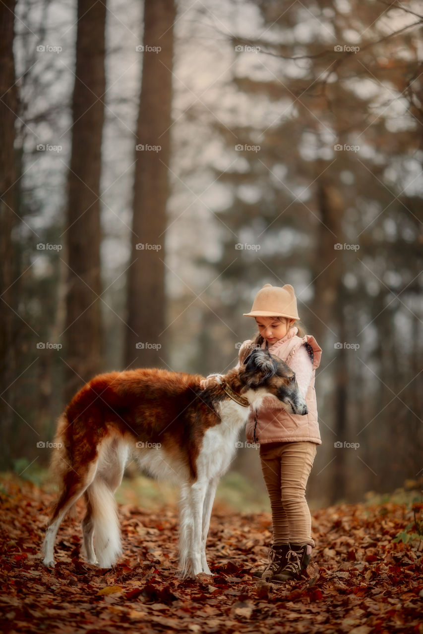 Cute smiling girl with borzoi dog in an autumn park 