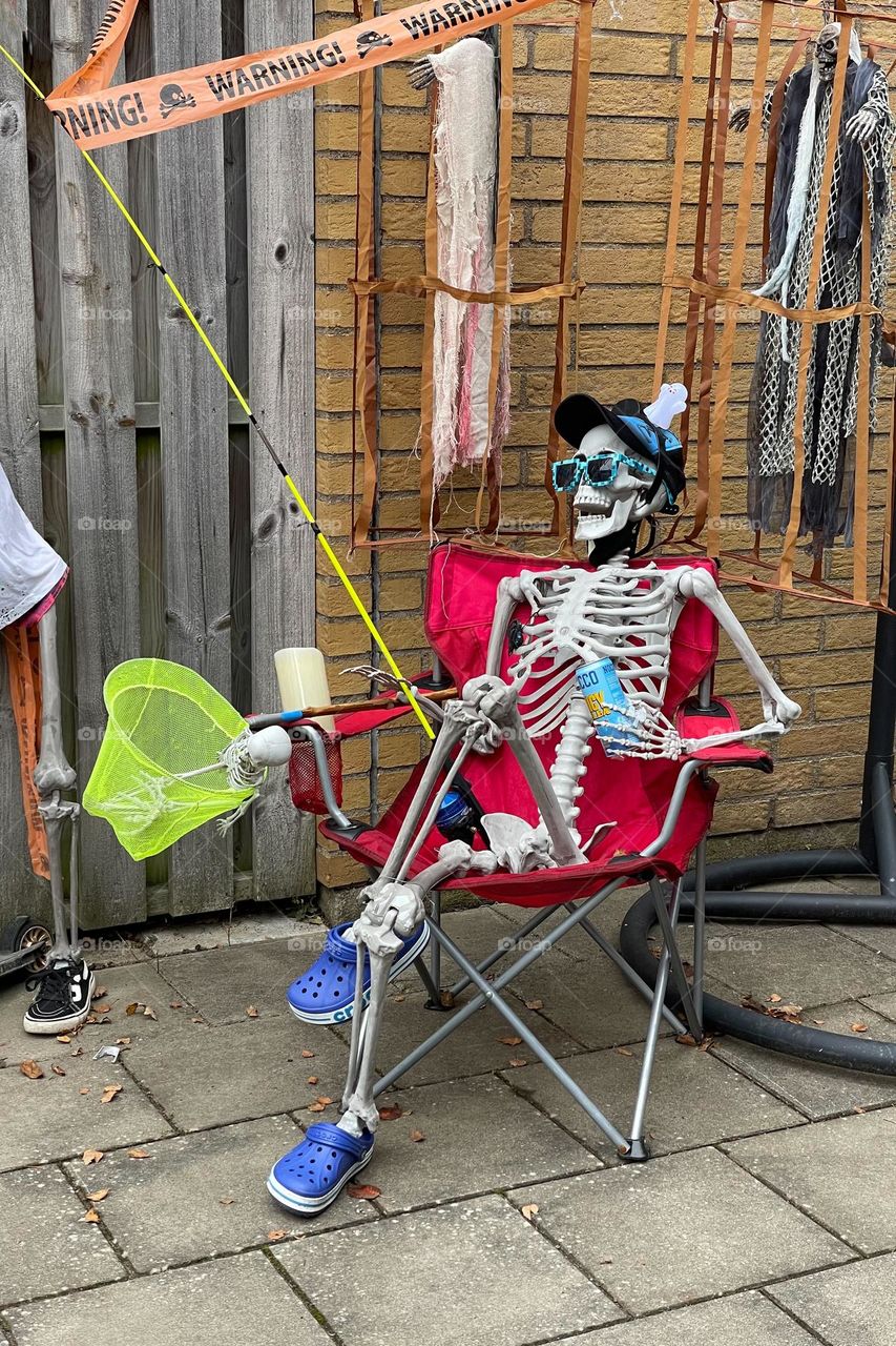 Halloween decorations, funny skeleton sitting in a chair 