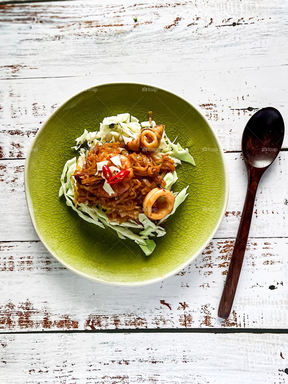 Seafood and flat noodle dish on a white wooden table