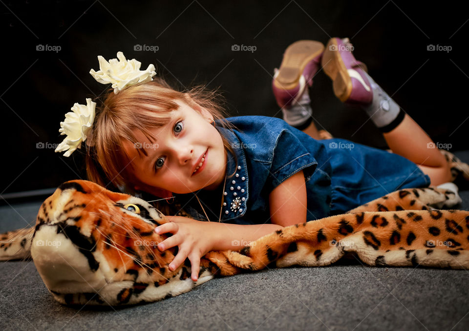 Beautiful little girl lying on the skin of a leopard.