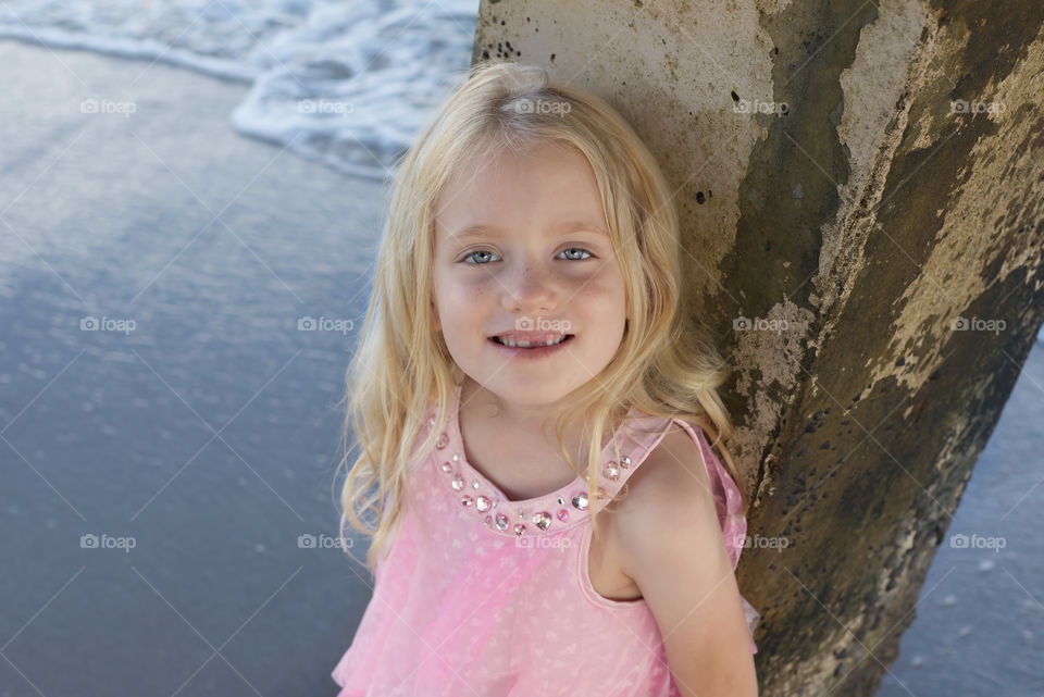 Girl smiling near a pier at the beach 