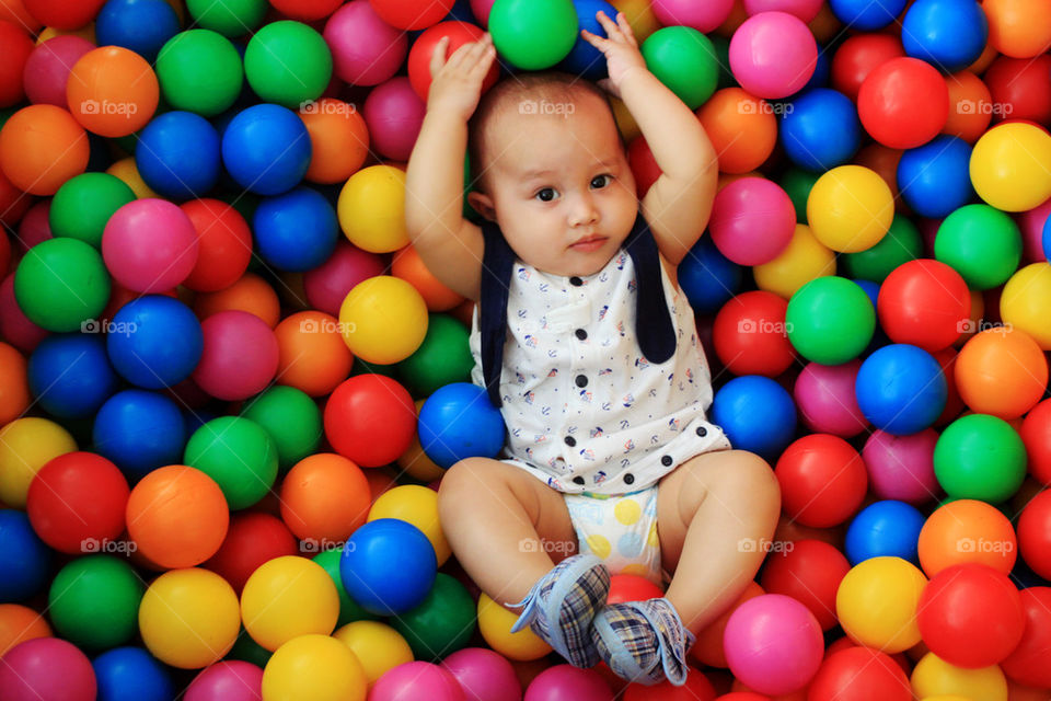 baby boy playing with multi color balls  