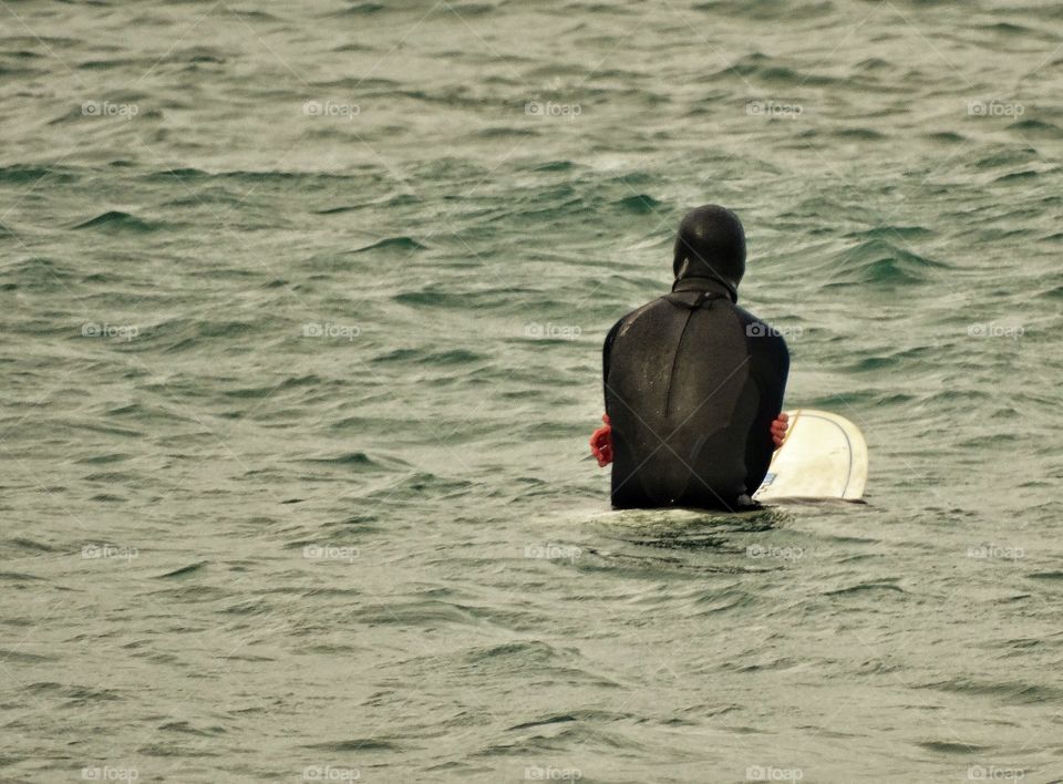 Wetsuit end surfer patiently waiting in the waters of Pacifica, California
