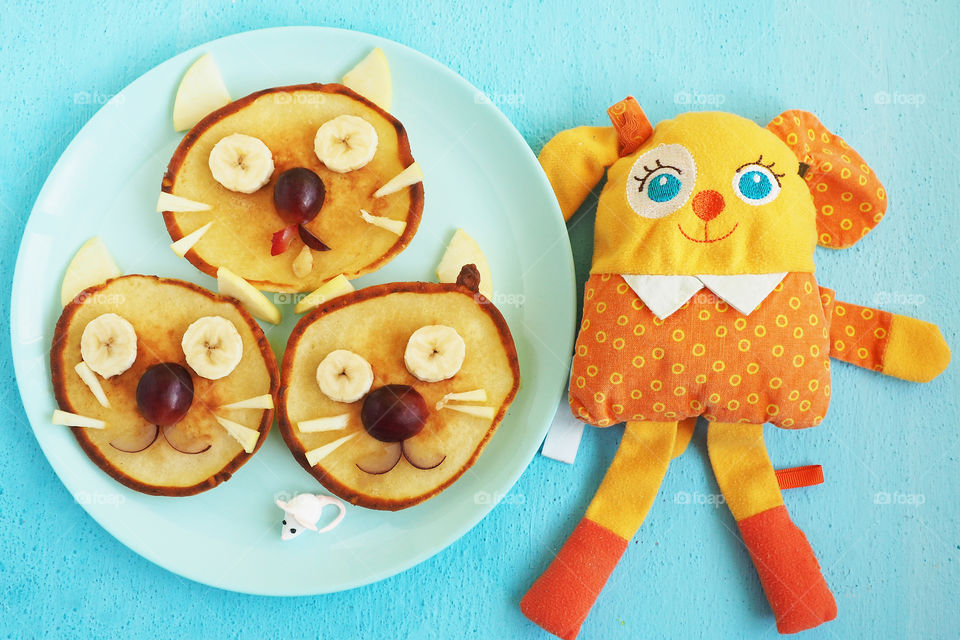 a plate of pancakes in the form of kittens and a dog toy on the table