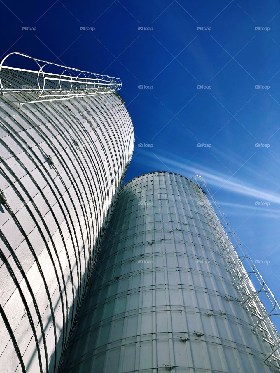 Silos in the sky, looking up towards the sky, blue skies with white silos, country portrait, peaceful quiet image, on the farm, in the countryside 