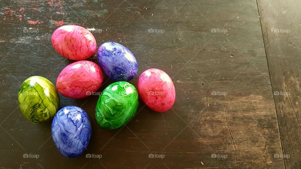 Seven colored Easter eggs lying on a wooden table