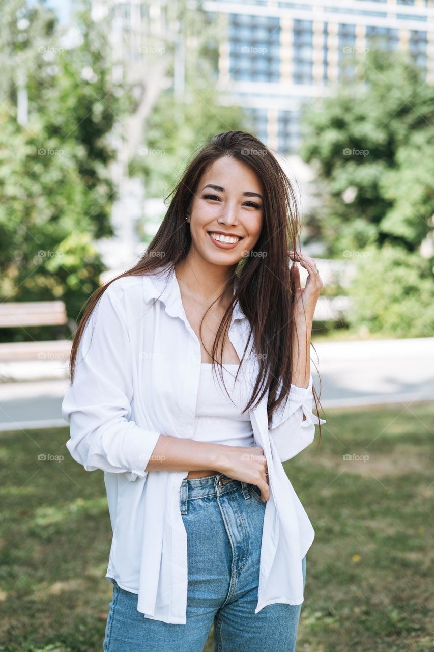 Portrait of young asian woman student with long hair in city park