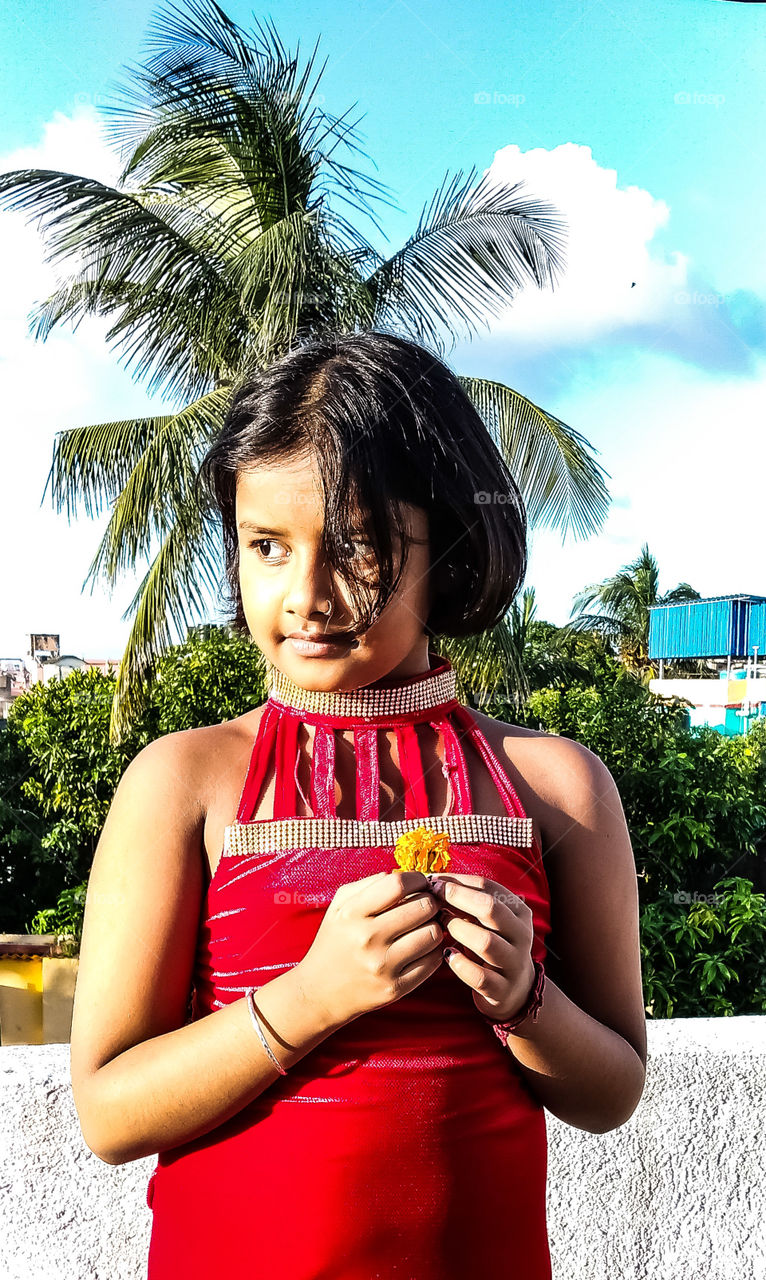 Portrait of a girl. headshot, close-up, trees, blue sky, holding, hands, red dress, Black hair, flowers, building, beautiful view, business, background wallpaper, kolkata bengal india,