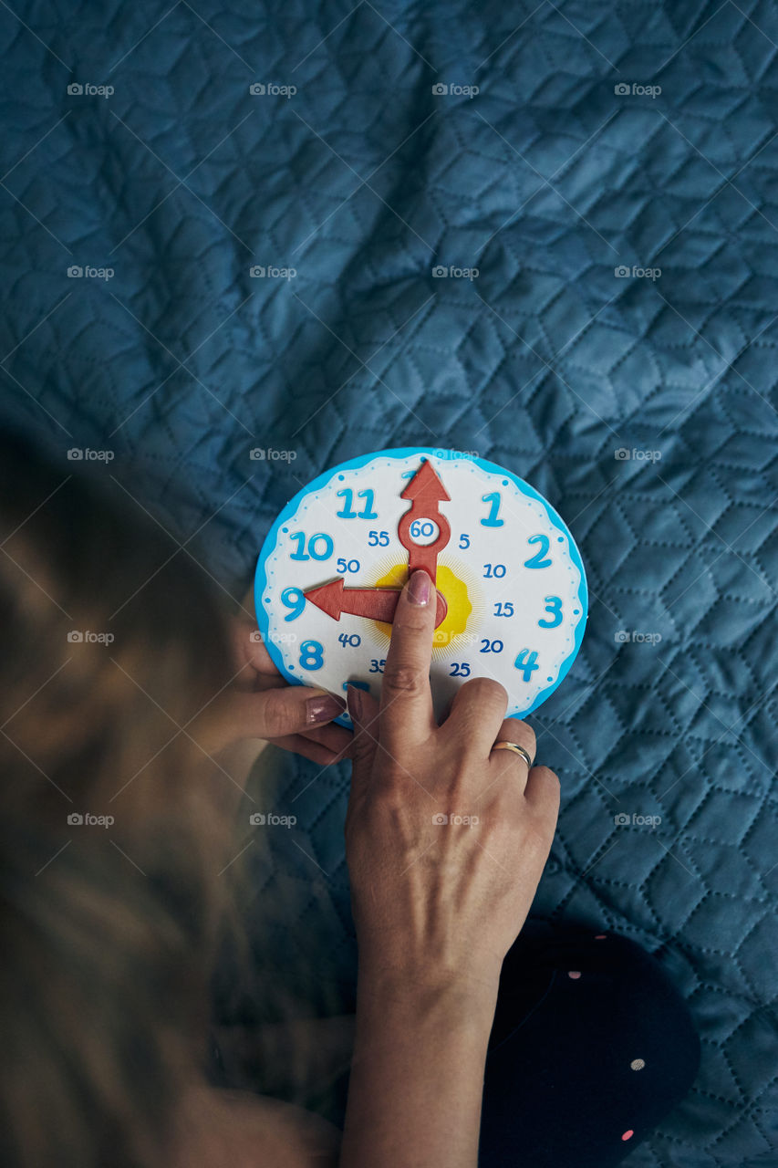 Kids learning how to tell time from clock and set the hands in the correct position. Teaching preschoolers tell time. Candid people, real moments, authentic situations