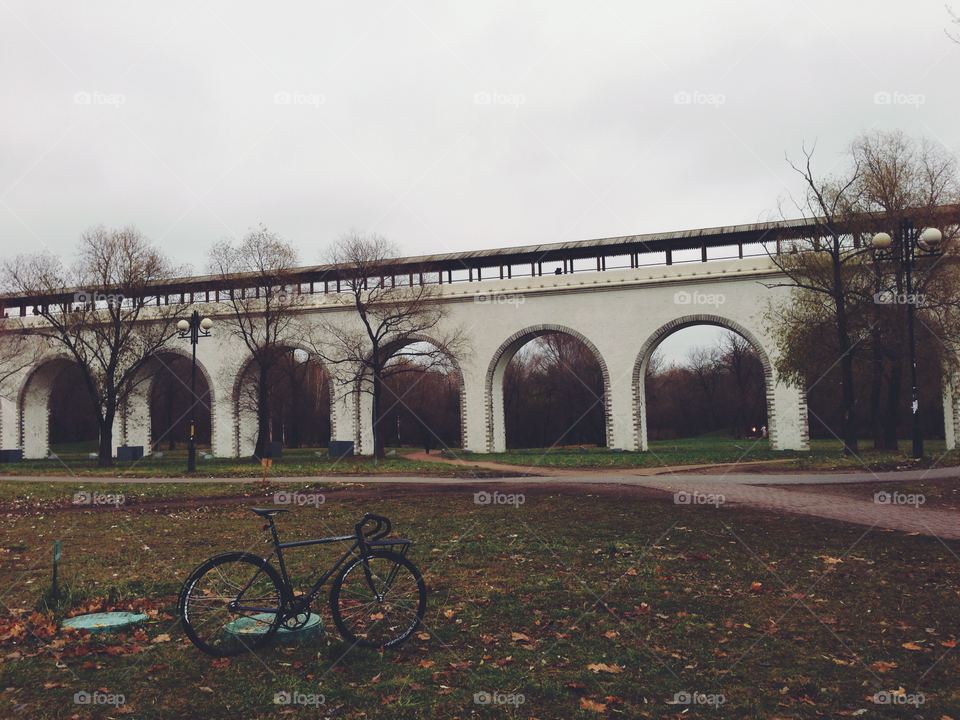 Grayish-black brakeless fixie bicycle in front of the huge white Rostokino aqueduct in Moscow