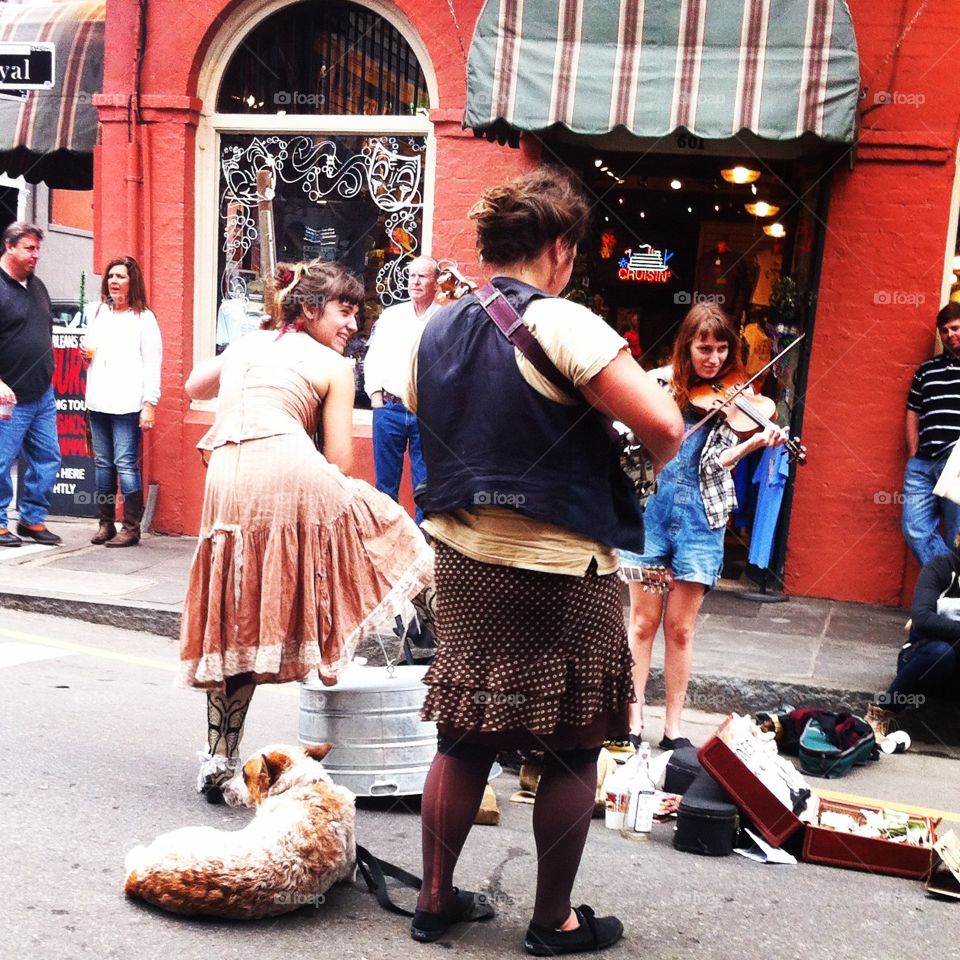 Street musician performers in New Orleans, Louisiana. A dog, a homemade bass, a violin, and an old suitcase for tips. 