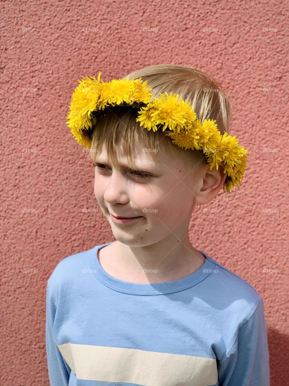 A child in a wreath of dandelions, cute boy smile