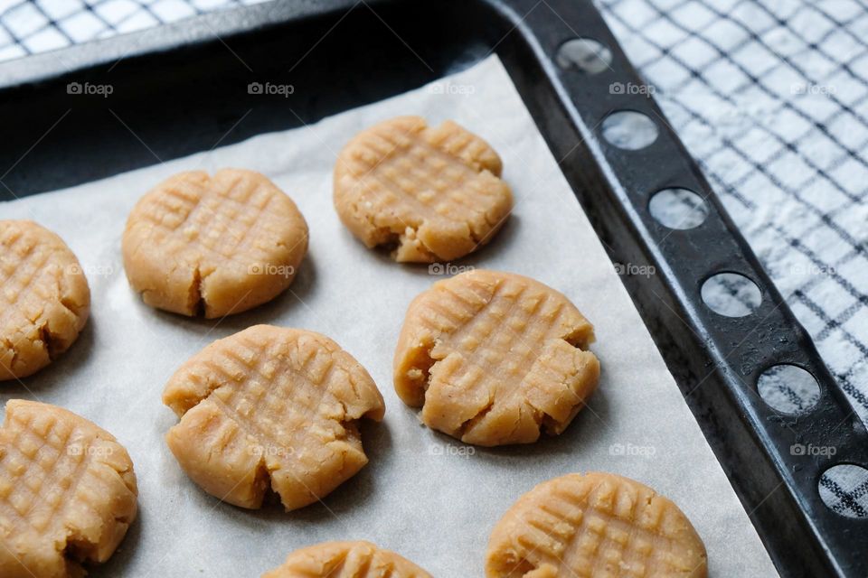 Close up of raw American peanut butter cookies on a baking sheet lined with baking paper laying on a checkred napkin