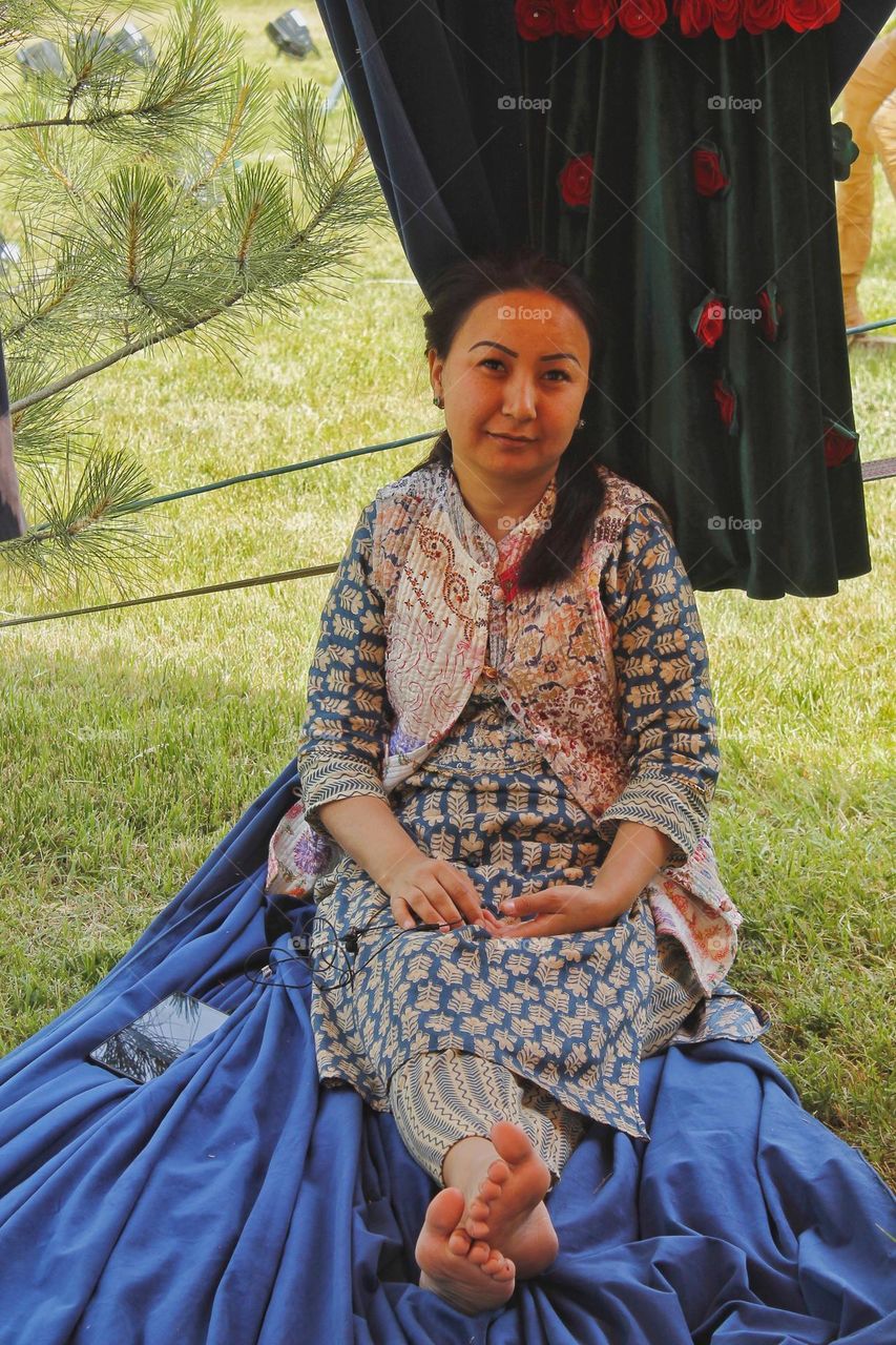 a woman of Asian appearance in national dress is resting on the grass on a summer day