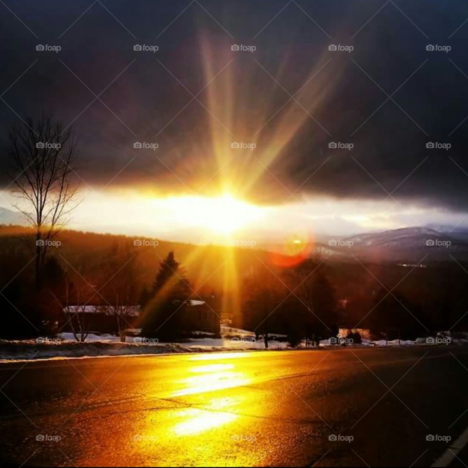 Sunlight on road during sunset near mountain