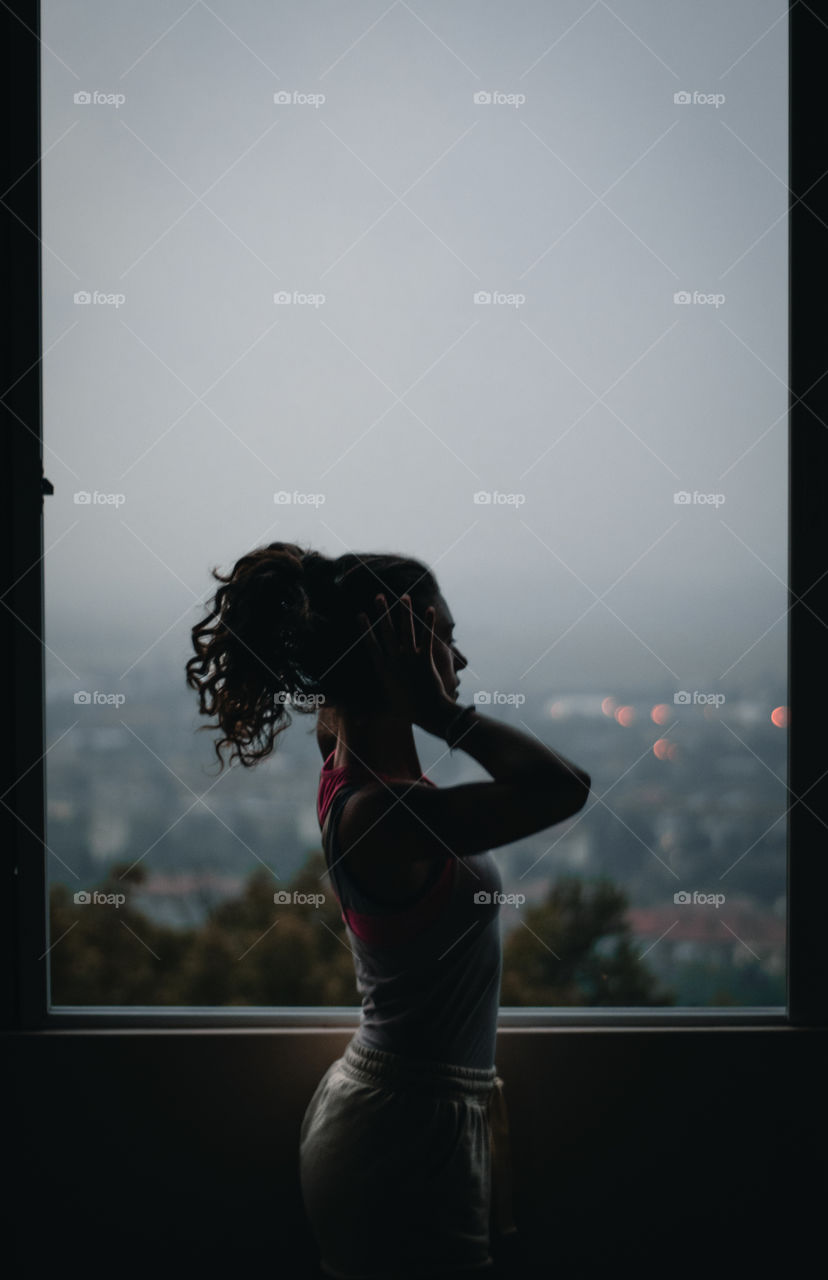 Girl in a silhouette in front of a window.