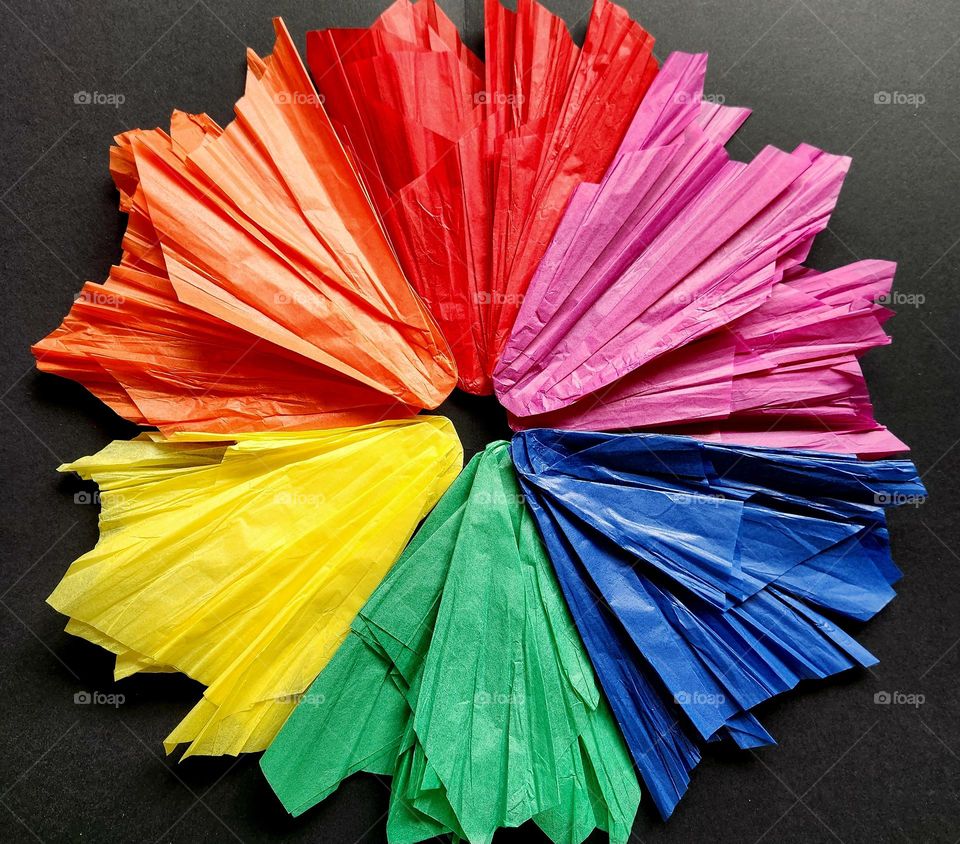 Complementary colours flatlay composed with coloured silk papers representing a flower on a black surface