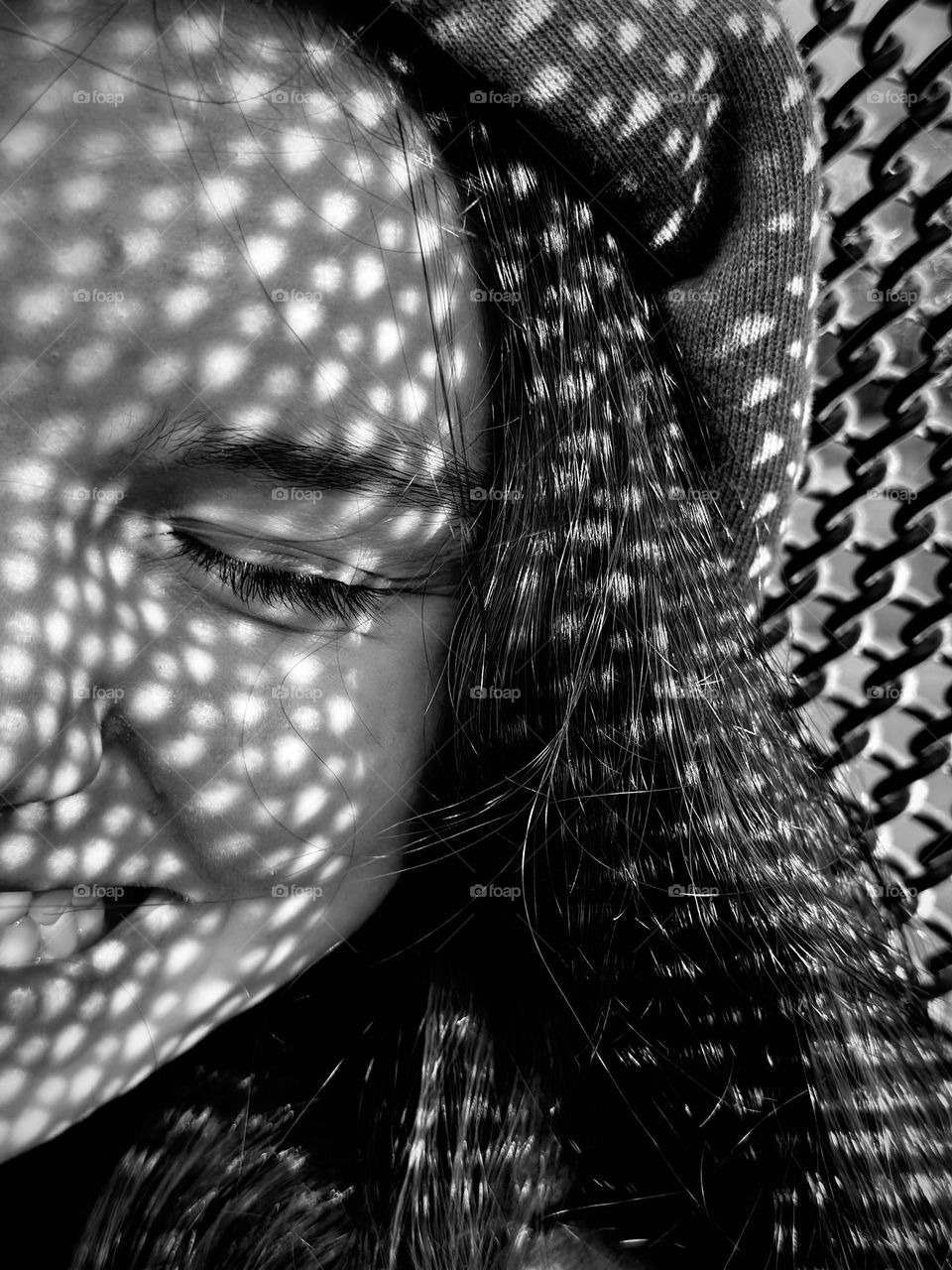 Smiling girl with the shadows of a fence on her face 